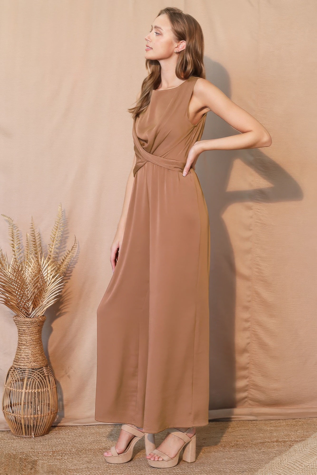 Elegant brown sleeveless maxi dress with waist tie, paired with beige heels for chic everyday style.