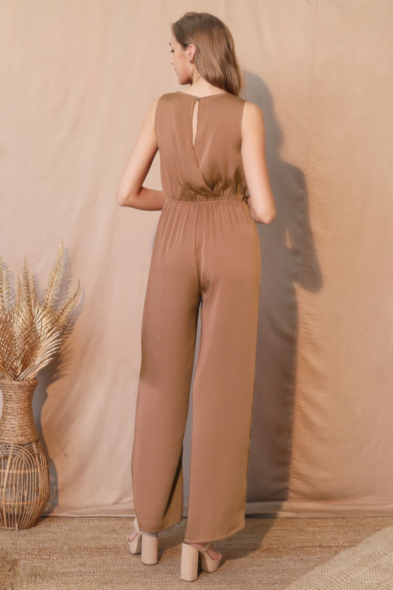 Brown sleeveless jumpsuit with wide legs and back slit, styled with block heels
