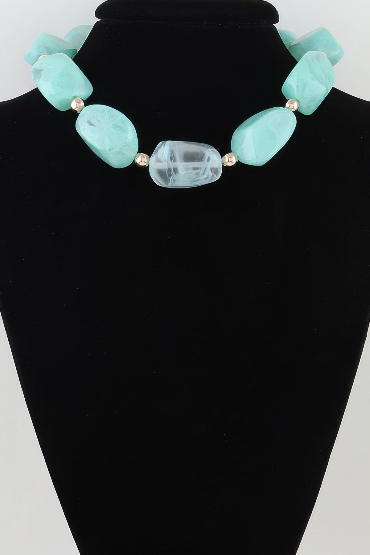 Turquoise statement necklace with faceted beads and gold spacers on black display
