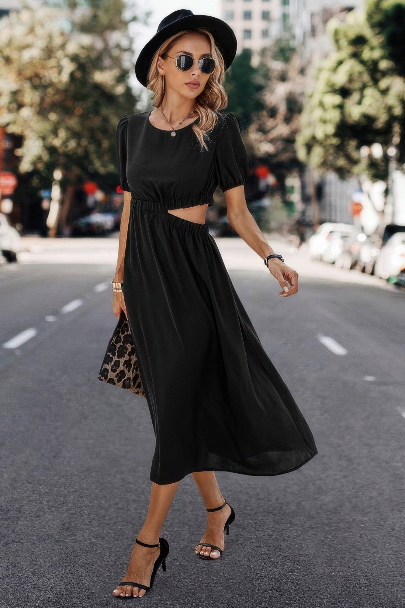 Woman in black cutout midi dress with puff sleeves, hat, and heels for stylish streetwear
