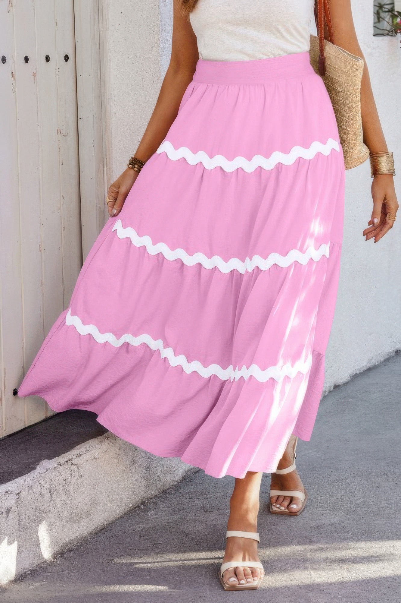 Pink tiered midi skirt with white ruffle trim, styled with white top and sandals for summer fashion
