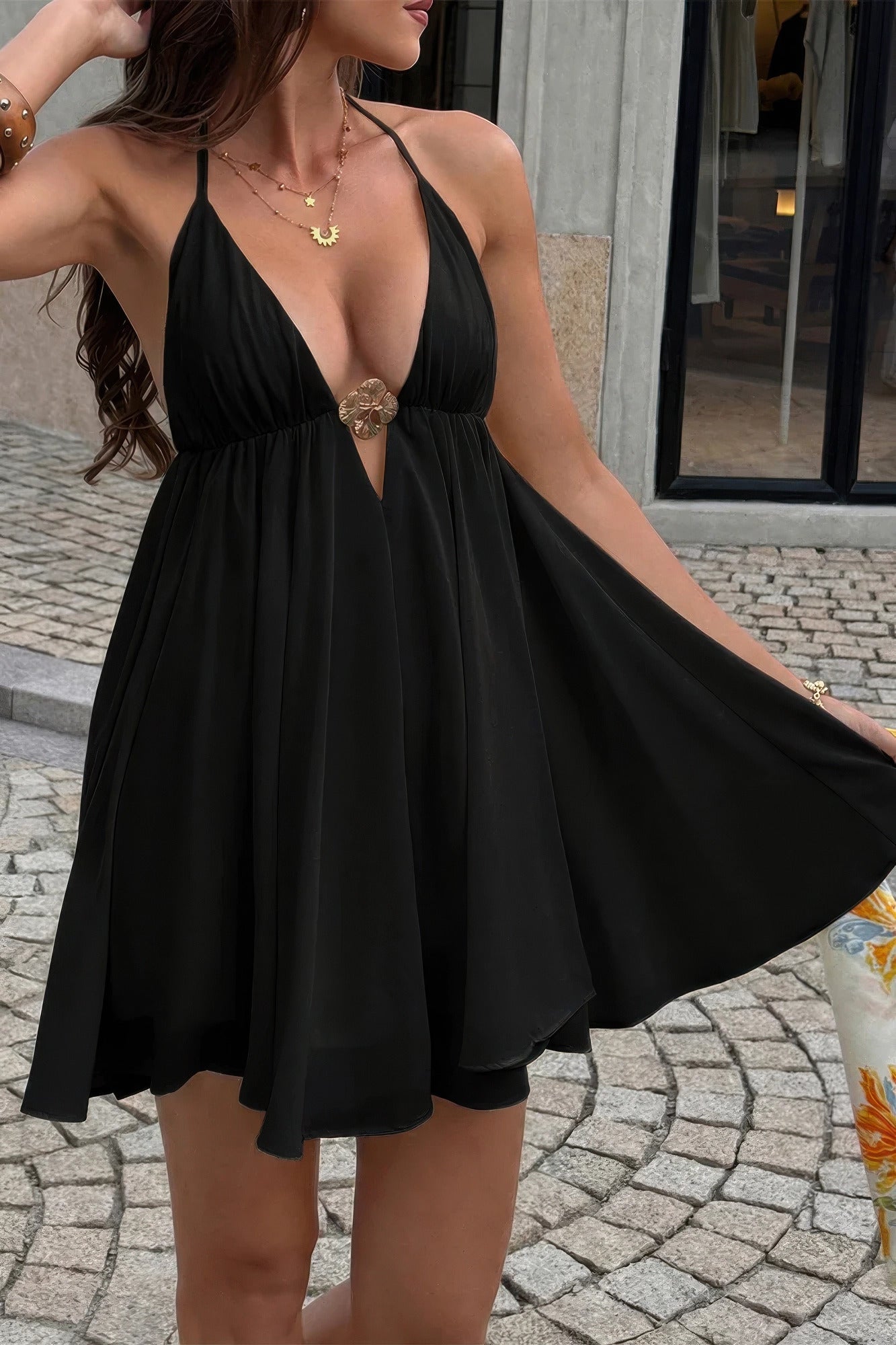 Black halter neck mini dress with deep V-neck and gold floral accent, perfect for stylish summer days.