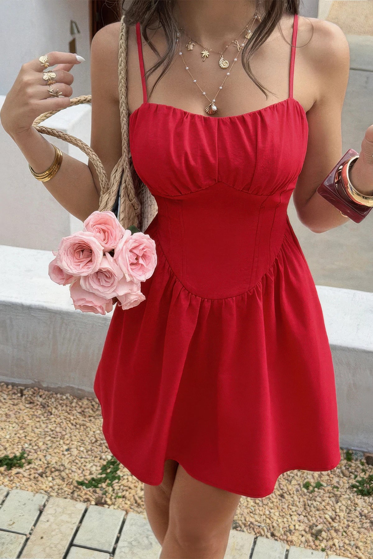 Red spaghetti strap dress with ruched bodice, pink roses, and gold jewelry for stylish summer wear