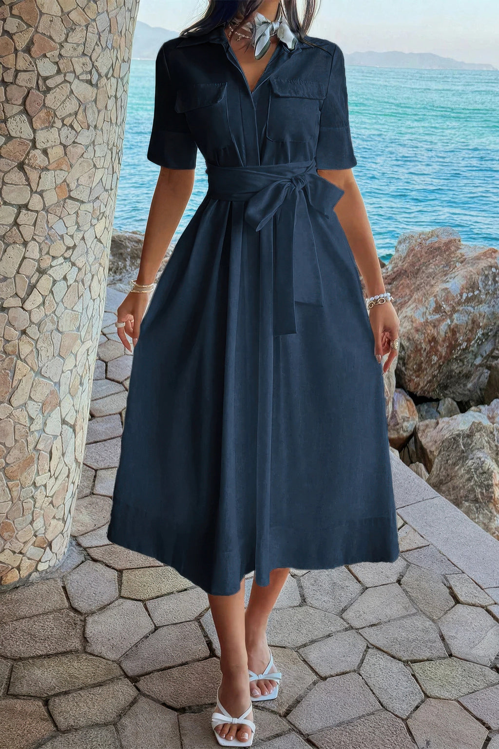 Navy blue shirt dress with tie waist, pockets, and midi skirt, styled with white sandals by the ocean
