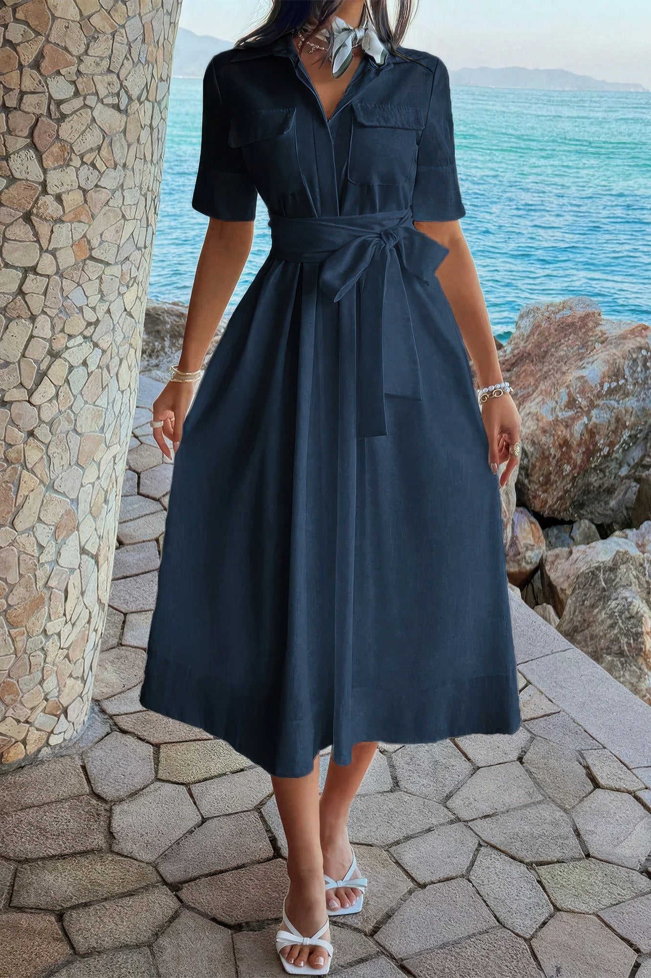 Navy blue shirt dress with tie waist, pockets, and midi skirt, styled with white sandals by the ocean