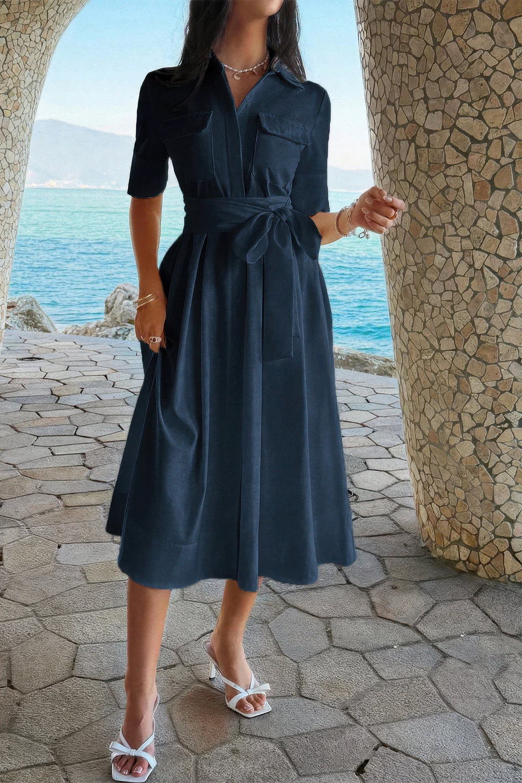 Navy blue midi shirt dress with tie waist, pockets, and white heels by the seaside