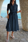 Navy blue midi shirt dress with tie waist, pockets, and white heels by the seaside
