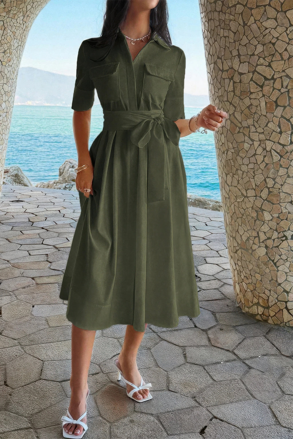 Olive green shirt dress with belt, pockets, and midi skirt, styled with white heels by the sea
